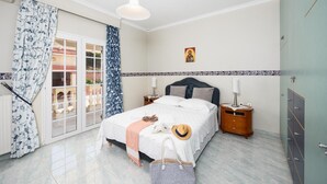 A bedroom with a bed, a nightstand, a lamp, a wardrobe, and a window with curtains.