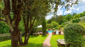 A garden with a pool, a stone bench, and a pathway. - Villa Bramasole Large Private Pool, WiFi (Sinalunga)