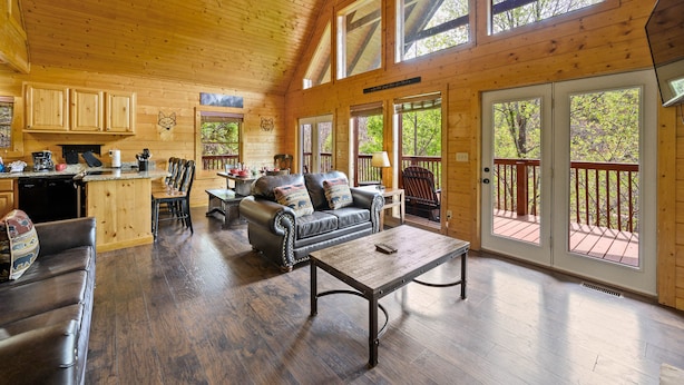 A spacious wooden cabin with a kitchen, dining area, and living room. - Free Attraction Passes | Firepit, Theater, Pool Table, Hot Tub, Private (Sevierville)