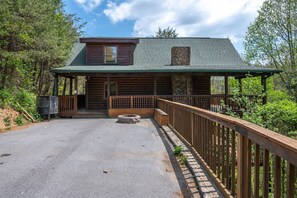A log cabin with a porch, a stone fireplace, and a fenced deck. - Free Attraction Passes | Firepit, Theater, Pool Table, Hot Tub, Private (Sevierville)