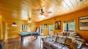 A wooden interior with a pool table, leather sofa, and ceiling fans. - Free Attraction Passes | Firepit, Theater, Pool Table, Hot Tub, Private (Sevierville)