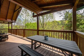A wooden deck with a picnic table and benches, surrounded by trees. - Free Attraction Passes | Firepit, Theater, Pool Table, Hot Tub, Private (Sevierville)