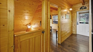 A wooden cabin interior with a sloped ceiling, a wooden door, and a bench in the background. - Free Attraction Passes | Firepit, Theater, Pool Table, Hot Tub, Private (Sevierville)