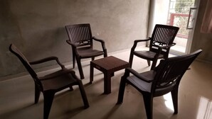 A room with four wooden chairs and a small square table, a concrete wall, and a glass door leading outside. - Close to the Border of Dominican Republic (Cap-Haitien)