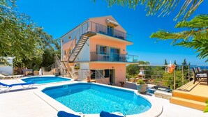 Un bâtiment à deux étages doté d’un espace piscine, comprenant des chaises longues et un escalier.