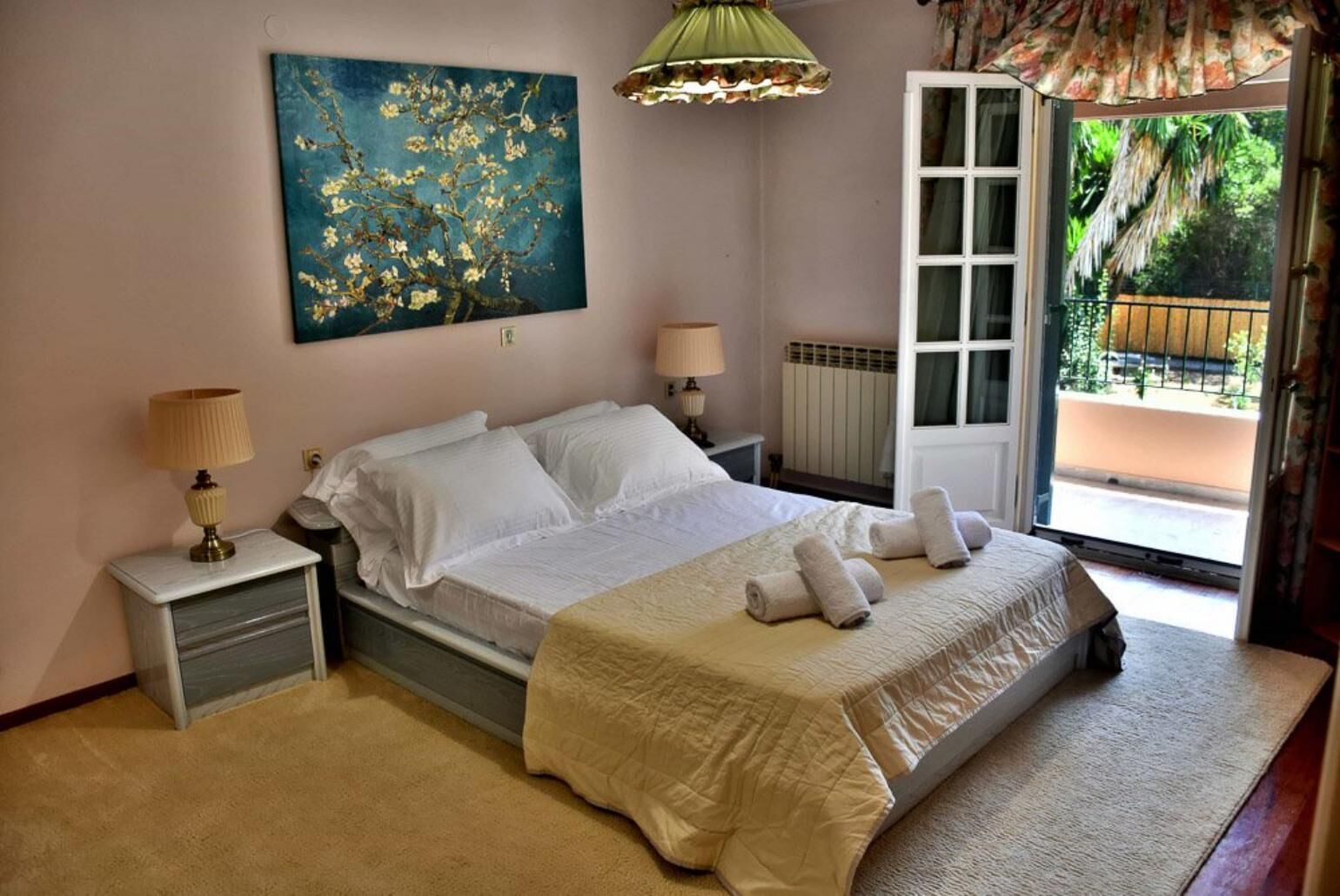 Een slaapkamer met een bed, twee nachtkastjes, een radiator en een raam met uitzicht op groen.