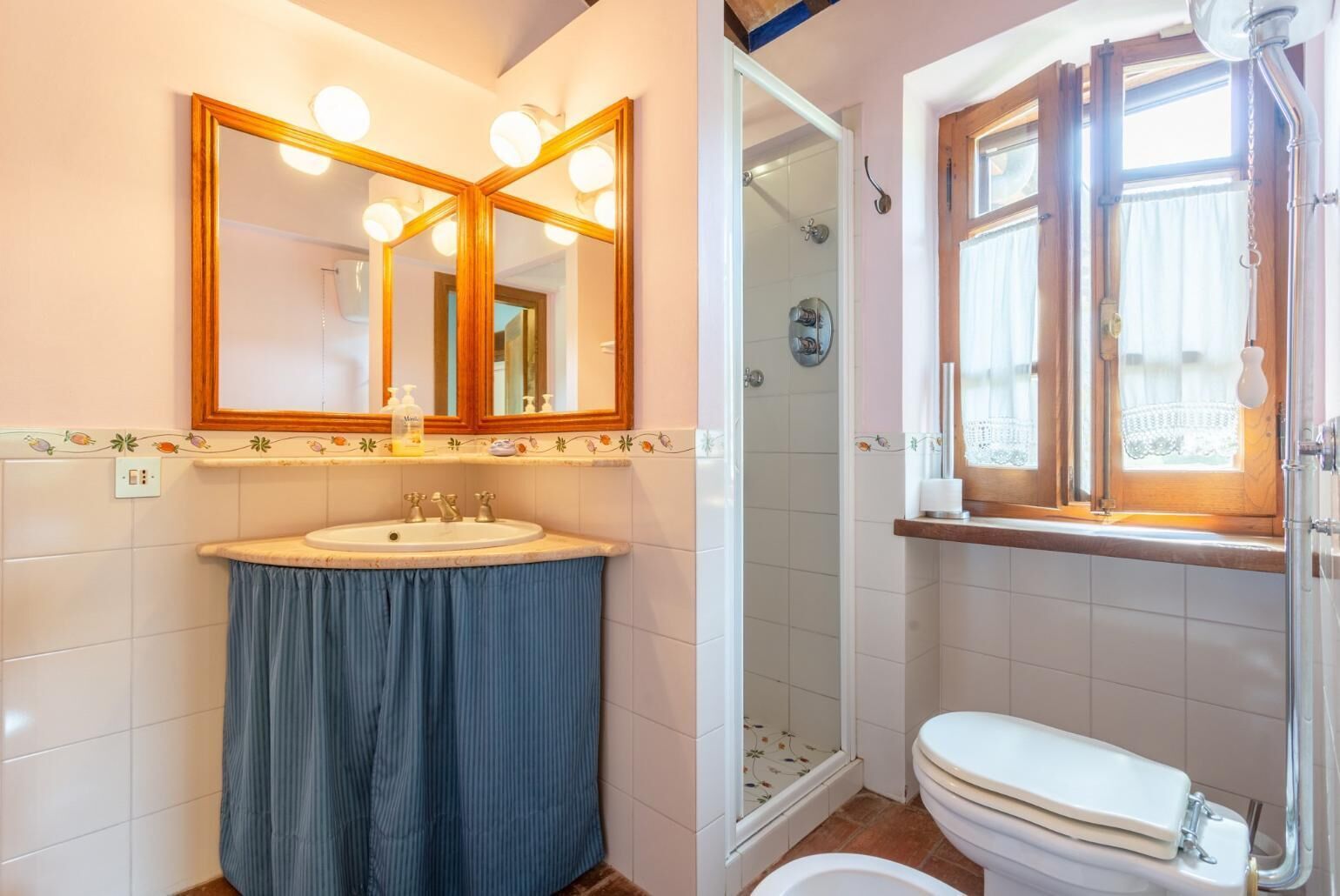 A bathroom with a large mirror, a sink, a toilet, and a shower.