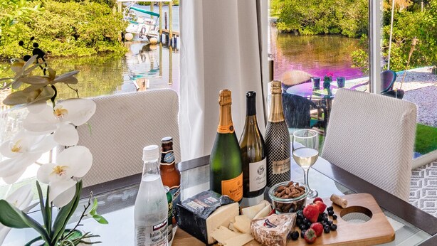 Ein Tisch mit einer Käseplatte, Weinflaschen, einer Wasserflasche und einer Pflanze.