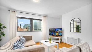 Una sala de estar moderna con un sofá, una mesa de centro y un televisor reproduciendo una película.