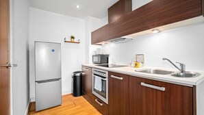 Una cocina compacta equipada con refrigerador, microondas, estufa y lavabo.