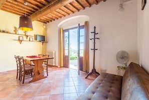 A cozy room with a wooden ceiling, a dining table with chairs, a sofa, a standing fan, and a television on the wall. - Villa Le Balze Large Private Pool, WiFi (Vinci)