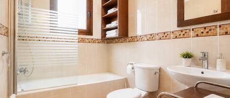 A bathroom with a shower, toilet, sink, and a mirror.