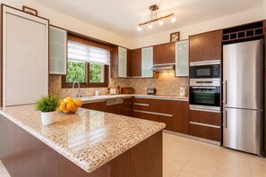 A modern kitchen with granite countertops, stainless steel appliances, and wooden cabinets.