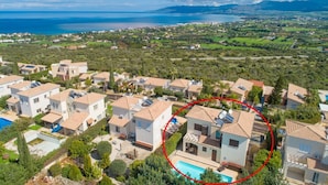 A residential area with houses, a swimming pool, and a view of the sea.