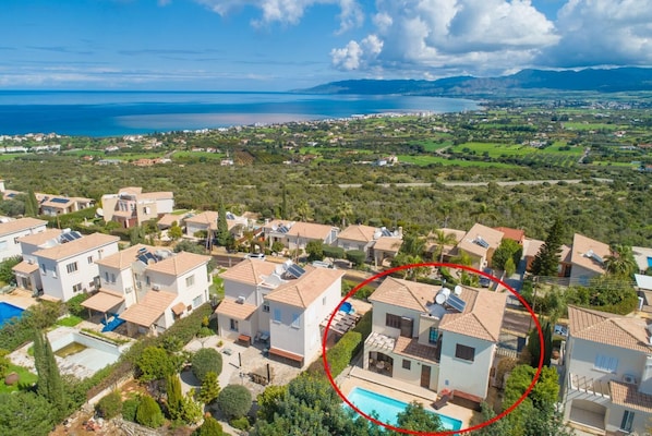 Zona residencial con casas, una piscina y vista al mar.