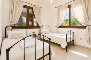 Un dormitorio con dos camas, cada una con estructura metálica, y una ventana con cortinas.