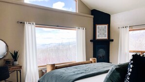Un dormitorio con una cama grande, cabecera de madera, chimenea y vistas al exterior.