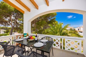 A covered outdoor dining area with a table set for two, chairs, and a bottle of wine. - Villa Luisa - Three Bedroom House, Sleeps 6 (Ferreries)