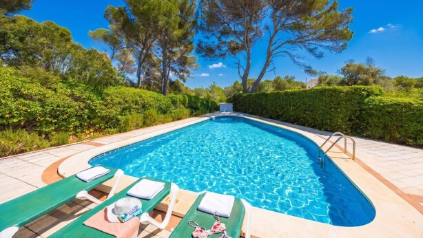 Une piscine avec des chaises longues et un ciel bleu azur.