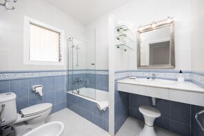 A bathroom with a toilet, bidet, and bathtub, a shower with glass doors, a sink with a mirror, and decorative tiles. - Villa Luisa - Three Bedroom House, Sleeps 6 (Ferreries)