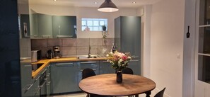 Une cuisine moderne avec des meubles gris, un plan de travail en bois et une table à manger agrémentée d’un vase de fleurs.