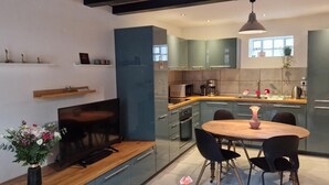 A modern kitchen with a dining area, built-in appliances, and a large window.