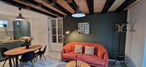 A modern living room with a wooden dining table, a sofa, and a pendant light.