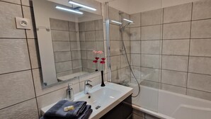 A modern bathroom with a bathtub, a sink with a mirror, and a shower.