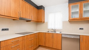 A kitchen with wooden cabinets, a stainless steel sink, and a dishwasher.