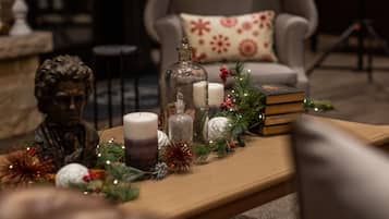 A cozy living room with a wooden coffee table adorned with Christmas decorations, including candles, a glass jar, and a statue.