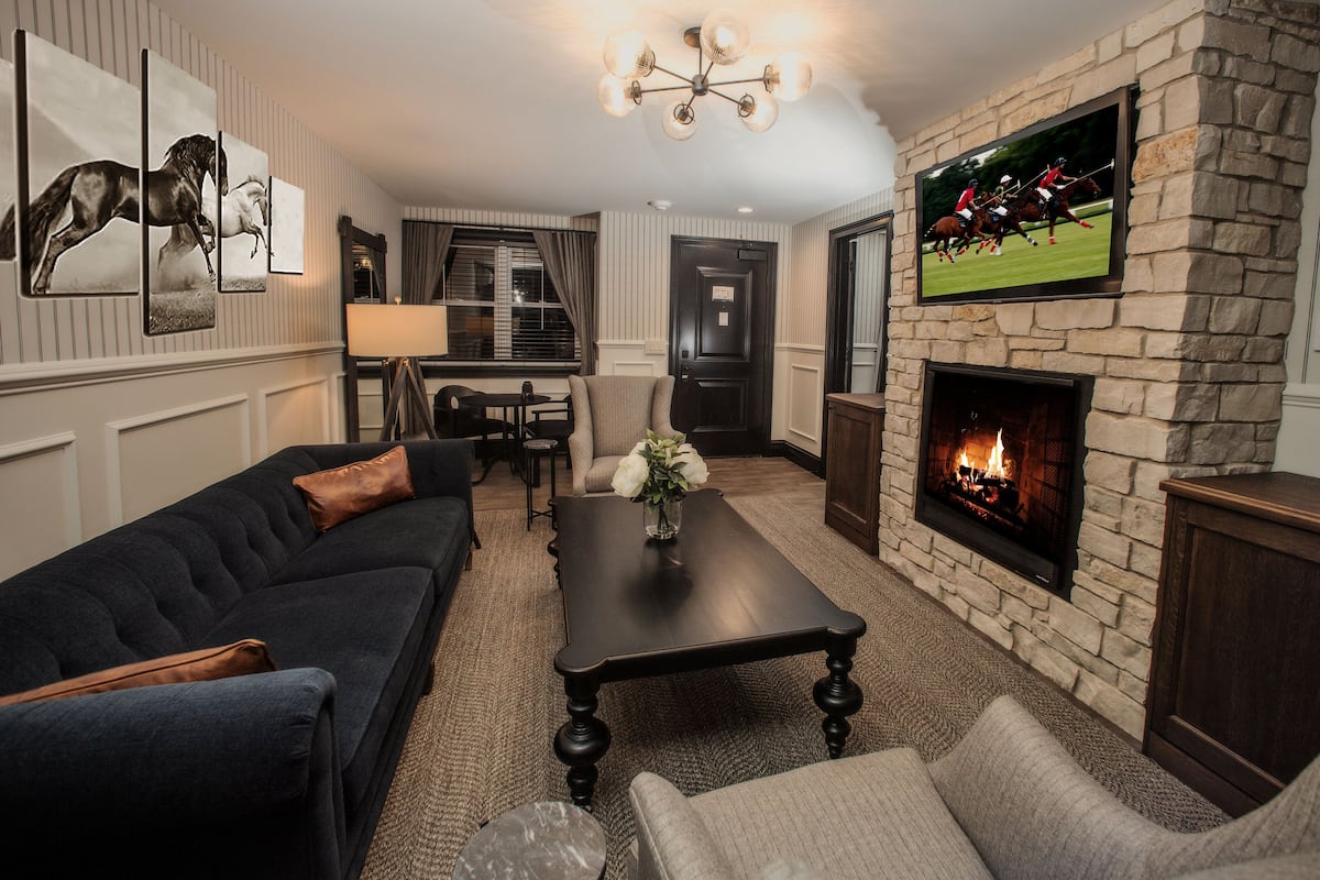 A living room with a fireplace, a sofa, a coffee table, and a television mounted on the wall.