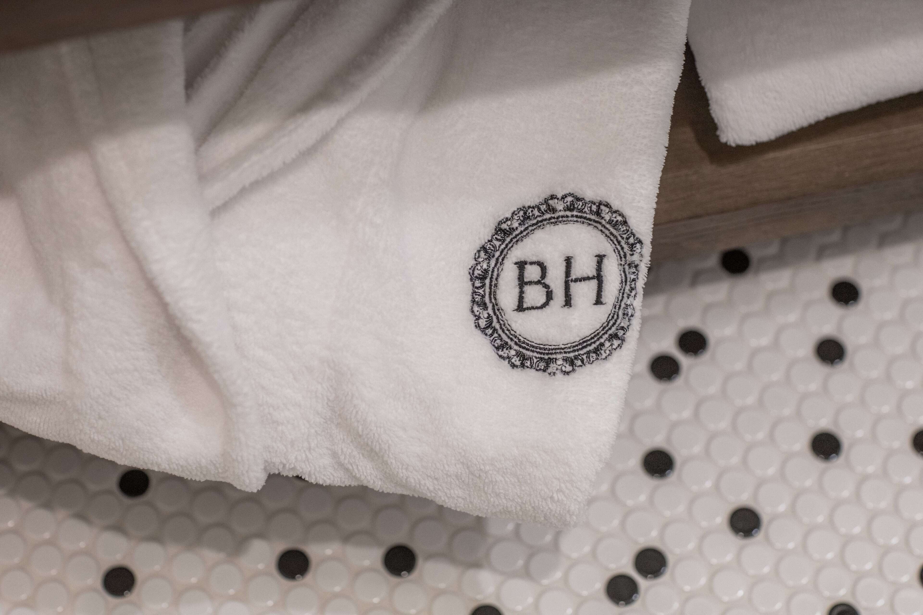 A white towel with a monogrammed logo on a textured surface.