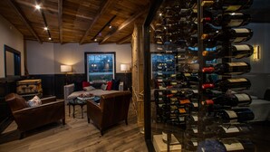 A room with a wooden ceiling, a wine rack, leather sofas, and a view through a glass wall. - The Belfry House (Williams Bay)