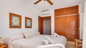A bedroom with a large bed, wooden wardrobe, and two framed pictures on the wall.