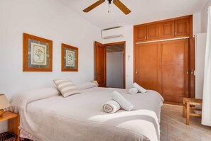 A bedroom with a large bed, wooden wardrobe, and two framed pictures on the wall.