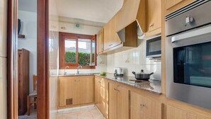 A kitchen with wooden cabinets, a stainless steel oven, a window, and a sink.