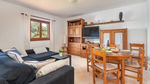 A cozy living room with a sofa, dining table, and TV.