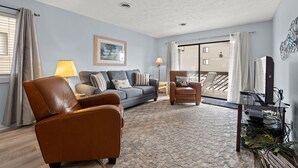 A living room with a sofa, armchair, and a TV stand with a plant. - Shipwatch Pointe I F117 Two Bedroom Condo First Floor Condo (Myrtle Beach)