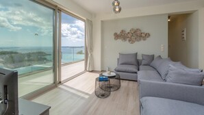 Una sala de estar moderna con un balcón grande, un sofá gris y un adorno de pared decorativo.