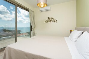 Un dormitorio con una cama grande, vista al mar y un equipo de aire acondicionado en la pared.