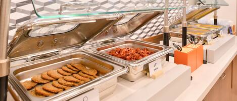 A buffet with labeled trays of turkey sausage and bacon.