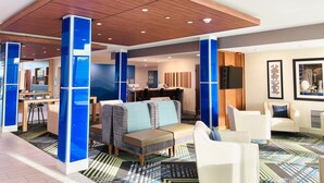 En moderne hotellobby med træloft, blå detaljer, et siddeområde med sofaer og stole, et spiseområde samt kunst på væggene.