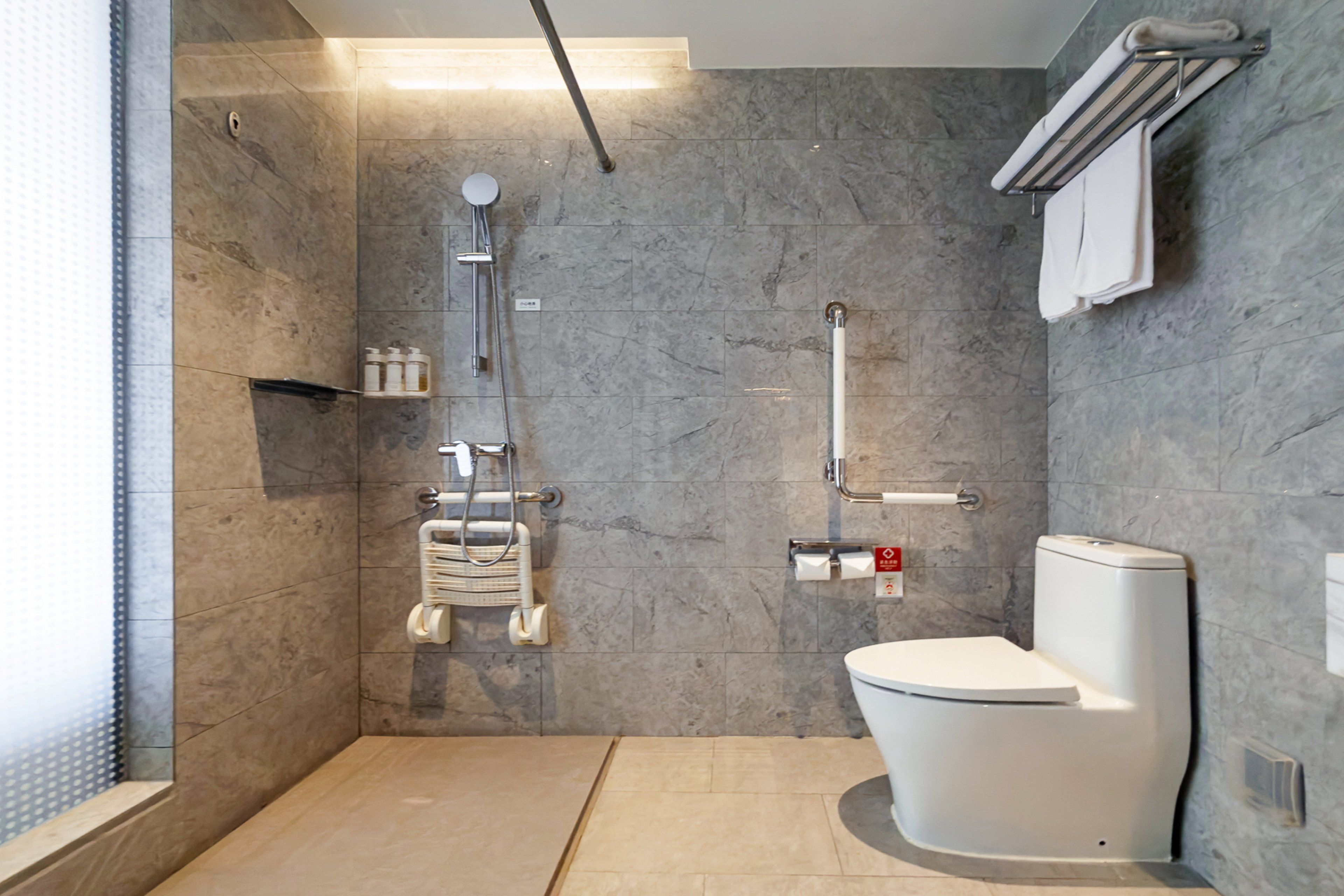A modern bathroom with a walk-in shower, a toilet, and a hand dryer.
