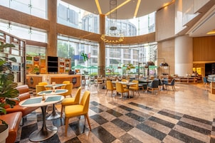 A spacious indoor area with multiple seating arrangements, a reception desk, and large windows allowing natural light.