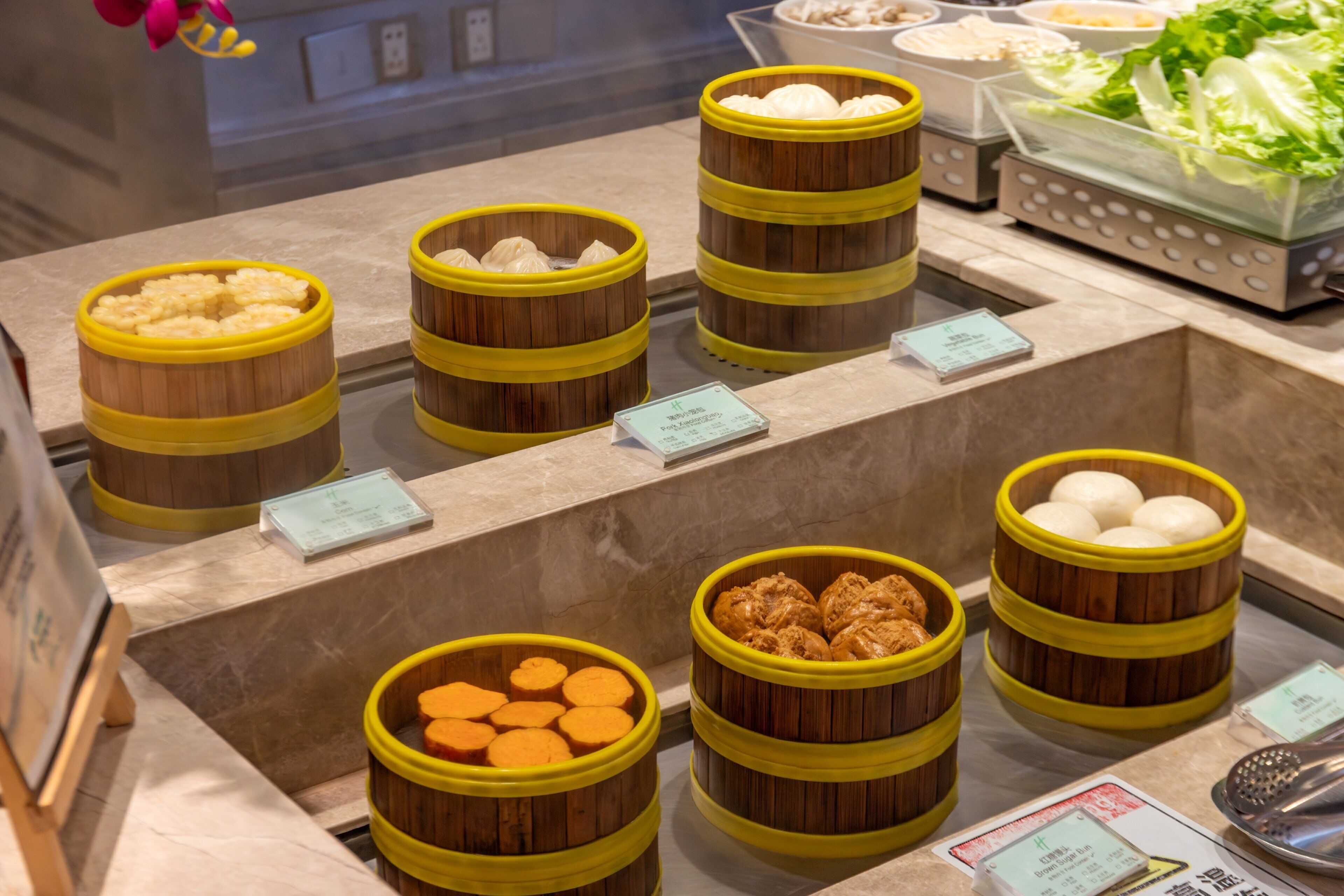 Een buffetgedeelte met diverse gerechten in houten manden, waaronder dumplings en andere specialiteiten.
