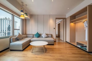 A modern living room with a sectional sofa, a round coffee table, and a view of the cityscape through large windows. - Holiday Inn Shanghai Nanjing Road by IHG (Shanghai)