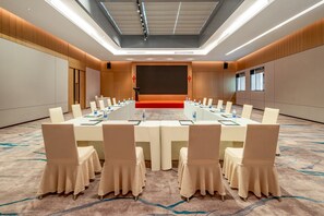 A conference room with a long table, chairs, a podium, and a large screen. - Holiday Inn Shanghai Nanjing Road by IHG (Shanghai)