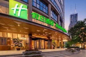 A hotel entrance with a prominent sign, a glass facade, and a modern architectural design.