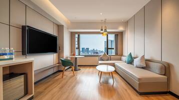 A modern living room with a flat-screen TV, a sofa, a small table, and a chair.