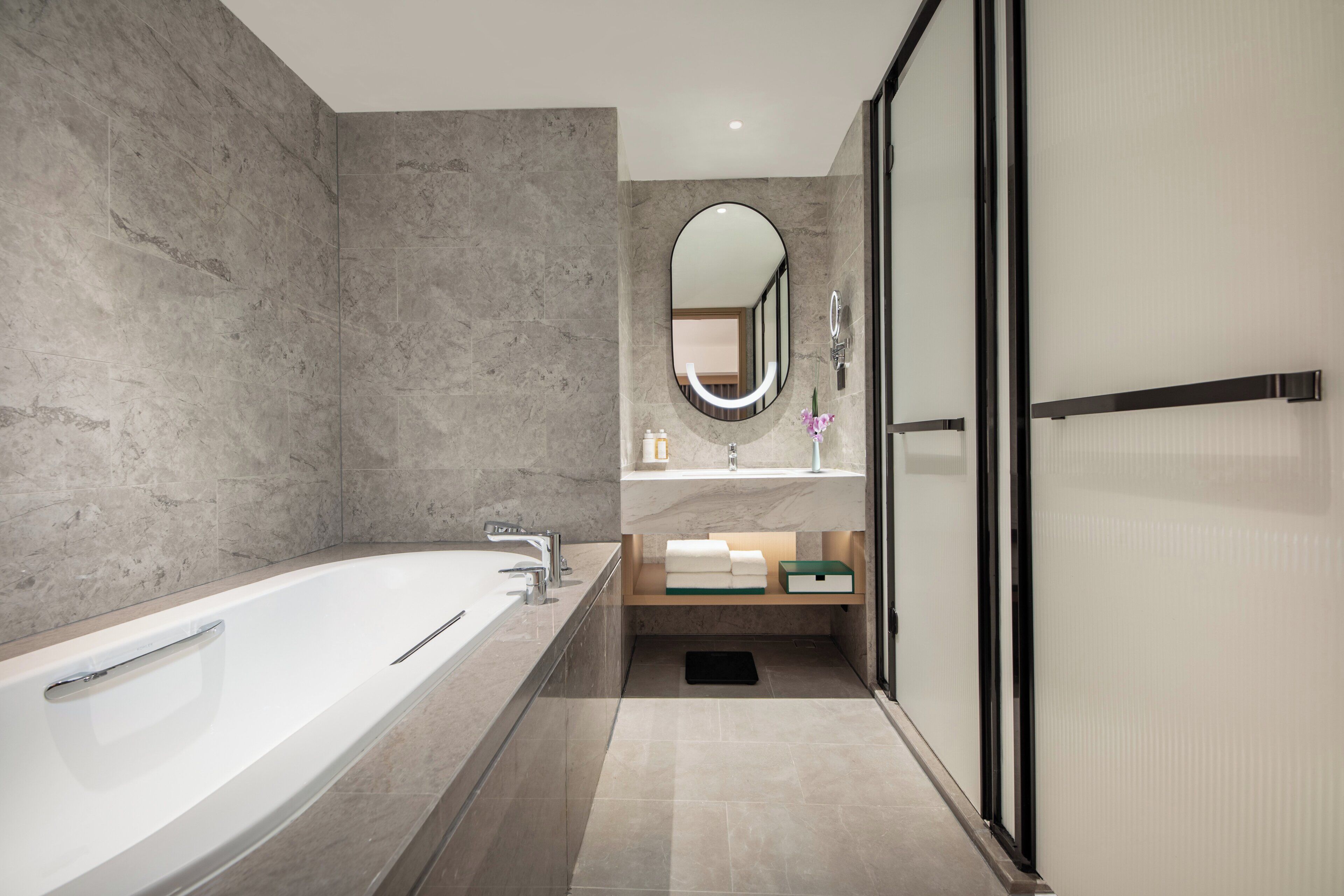 A modern bathroom with a large bathtub, a vanity with a mirror, and a shower area.